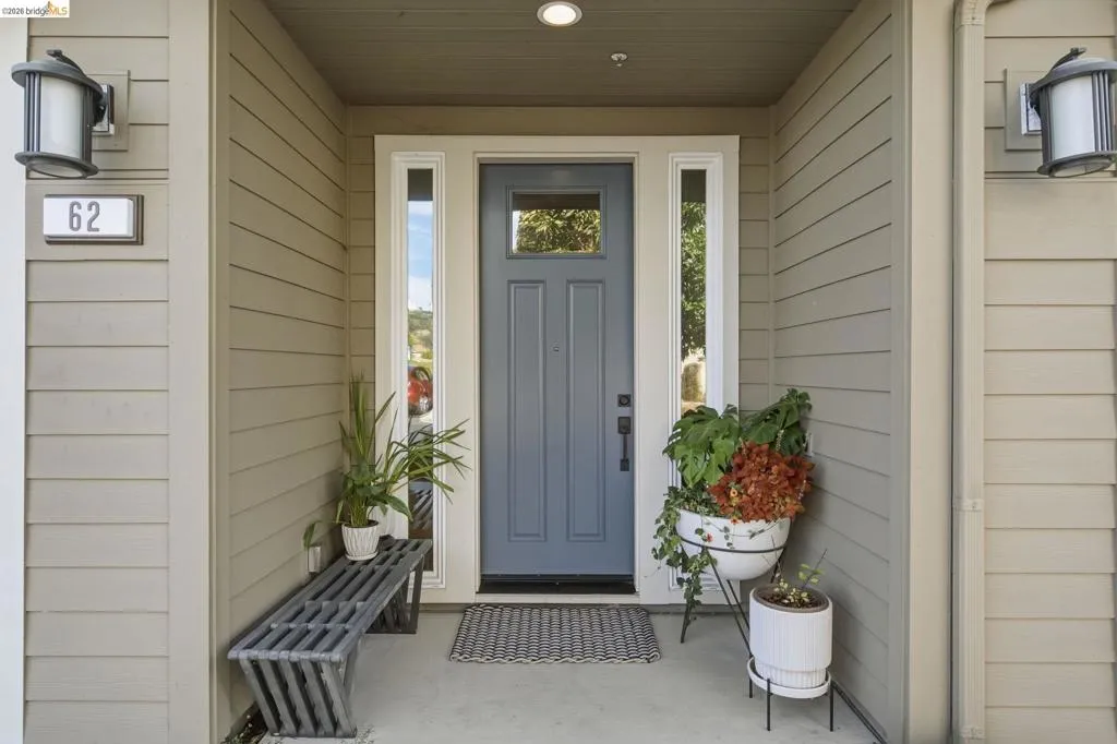 Recessed entry featuring a paneled door with glass insert, two sidelight windows, and horizontal siding