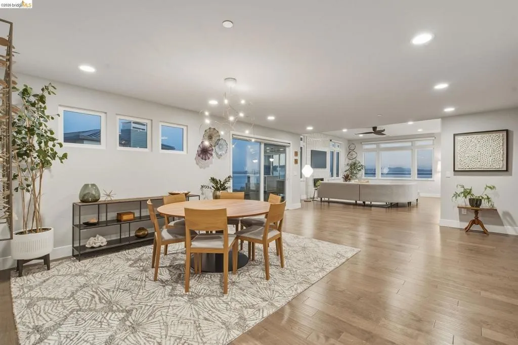 Open-concept living area featuring light wood-finish flooring, recessed lighting, and expansive windows