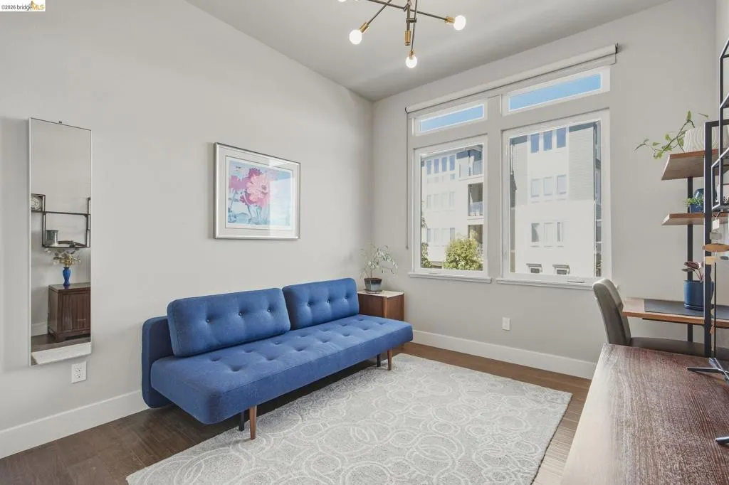 Vaulted ceiling, wood-finish flooring, abundant natural light, multiple windows, and a built-in shelving unit