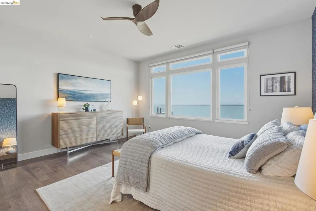 Expansive windows, wood-finish flooring, ceiling fan, and built-in cabinetry