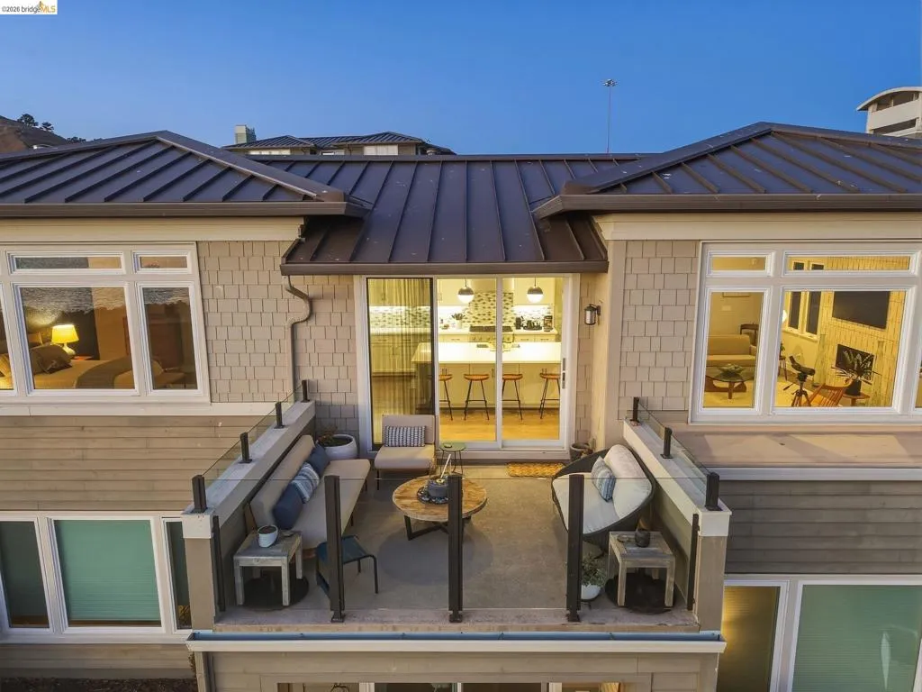 Private outdoor patio with glass railing, sliding glass door entry, and shingle siding