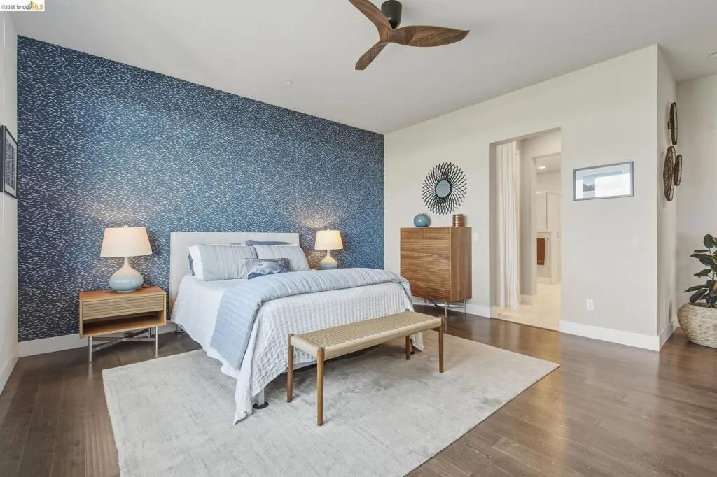 Wood-finish flooring, accent wall with patterned wall covering, ceiling fan with wood-look blades, and recessed lighting