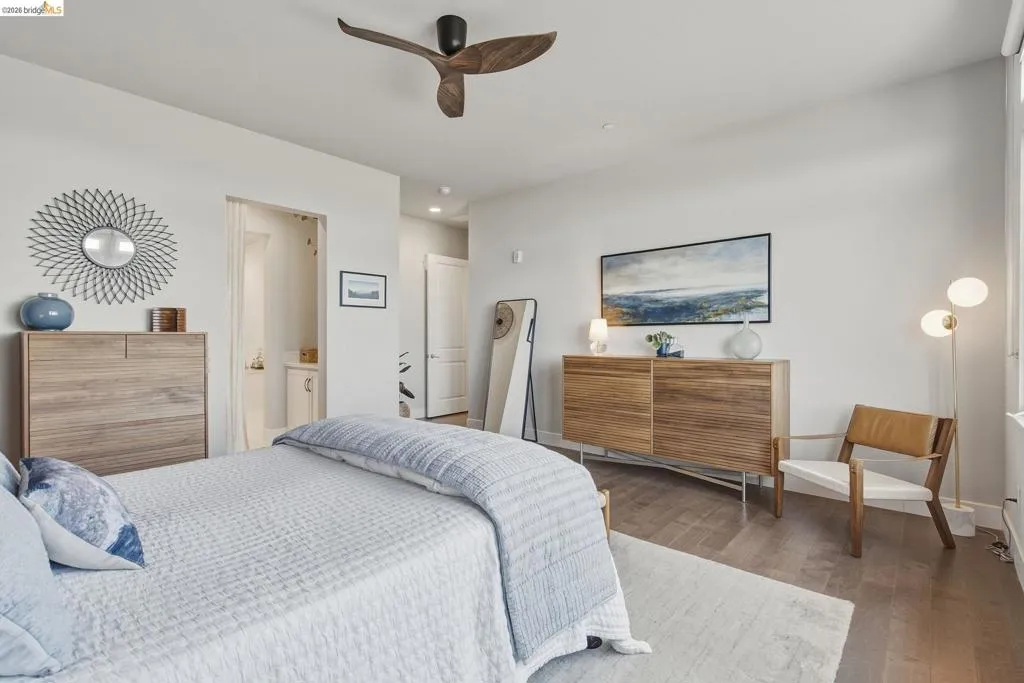 Wood-finish flooring throughout, featuring a modern ceiling fan with wood-tone blades, recessed lighting, and a built-in wall niche