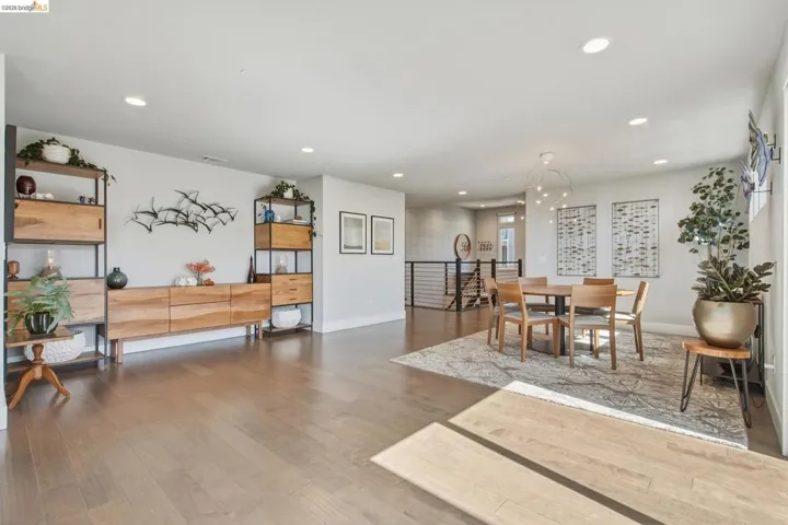 Expansive living area with wood-finish flooring, recessed lighting, and a modern chandelier