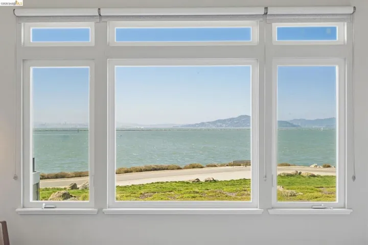 Expansive window wall with multiple panes, featuring white trim and roller shades