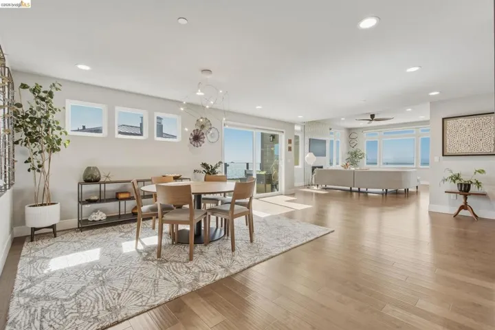 Open-concept living area with wood-finish flooring, recessed lighting, expansive windows, and a sliding glass door