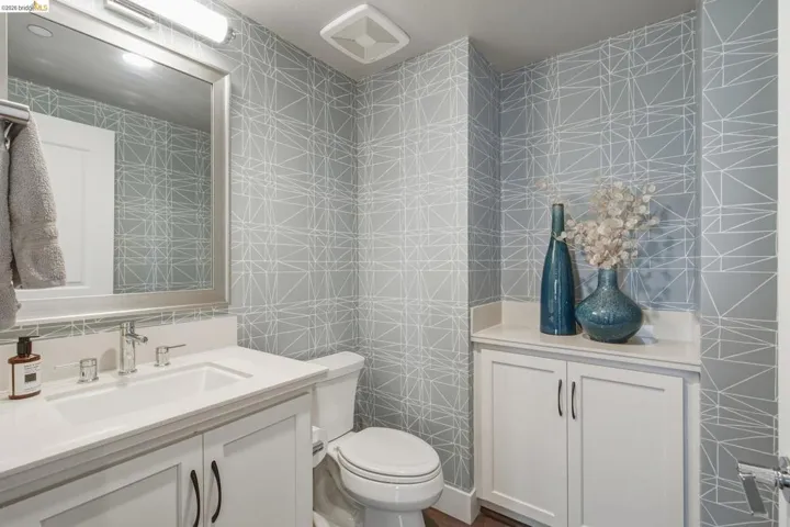 Built-in white cabinetry, integrated sink, wall-mounted mirror, and geometric pattern wall covering