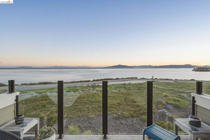 Glass panel railing system with dark posts, offering unobstructed water and distant city outlines