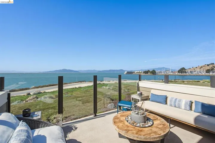 Outdoor patio with a glass railing, offering expansive water and marina scenery