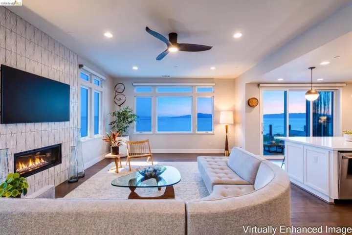 Open concept living space featuring a linear fireplace with textured tile surround, recessed lighting, and a ceiling fan