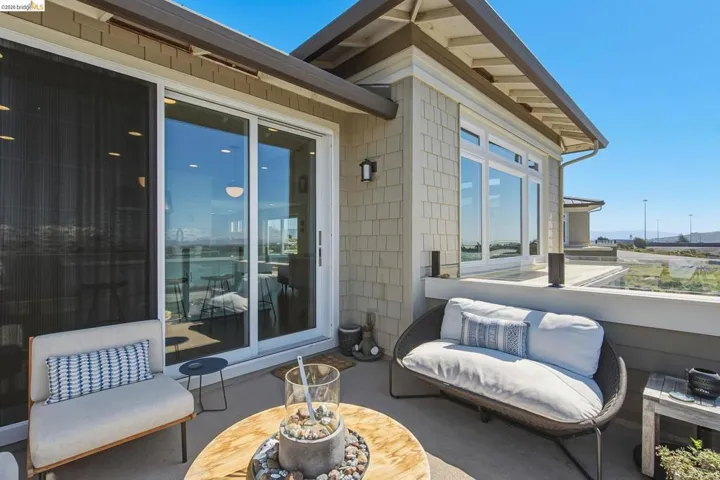 Spacious patio featuring a glass railing, large sliding glass doors, and shingle siding