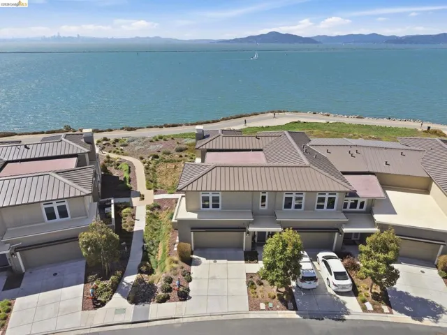 Waterfront property featuring a walking path, multi-level design, attached garages, and a metal-seam roof