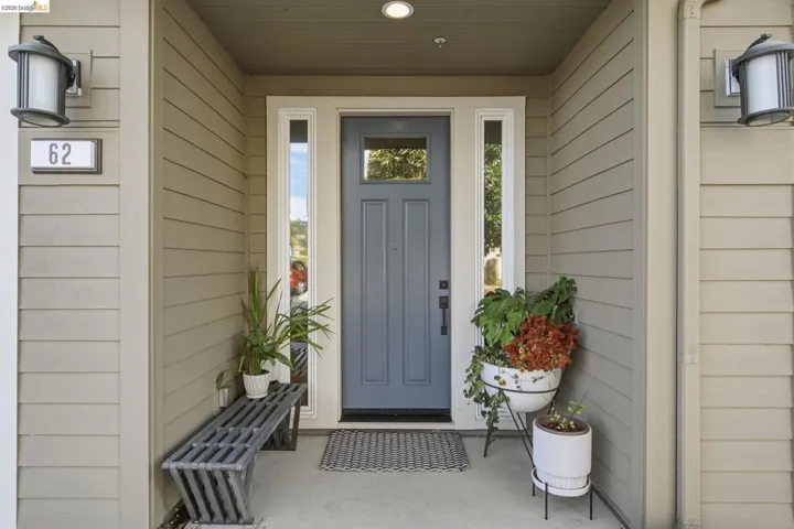 Recessed entry featuring a paneled door with glass insert, two sidelight windows, and horizontal siding