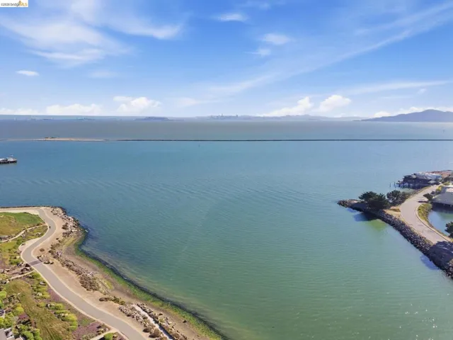 Expansive waterfront with a visible shoreline path and distant cityscape