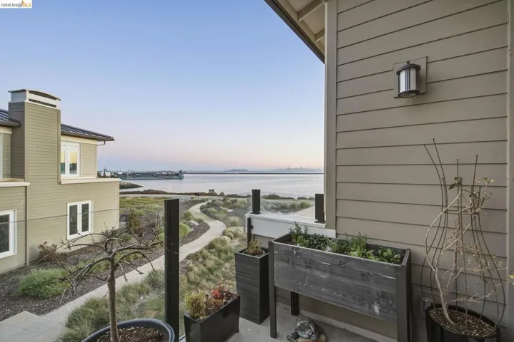 Balcony featuring a glass railing, exterior siding, and a wall-mounted light fixture