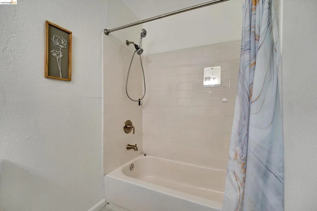 Bathtub with subway tile surround, brushed nickel fixtures, and a shower niche