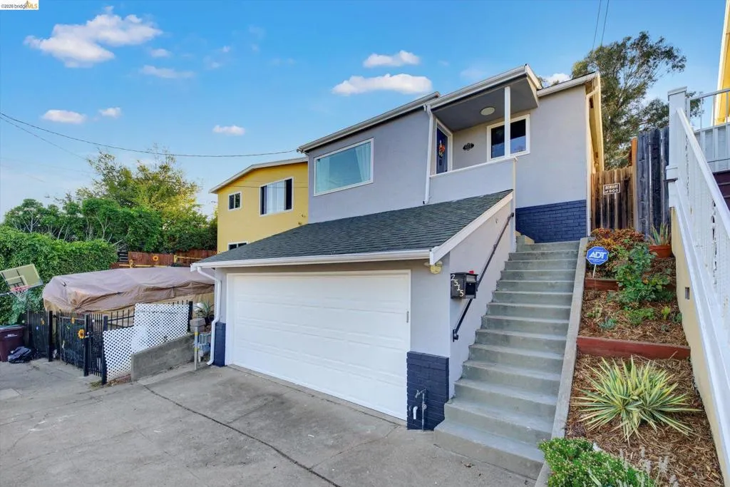 Contemporary exterior with a two-car garage, concrete driveway, and concrete steps with a black handrail