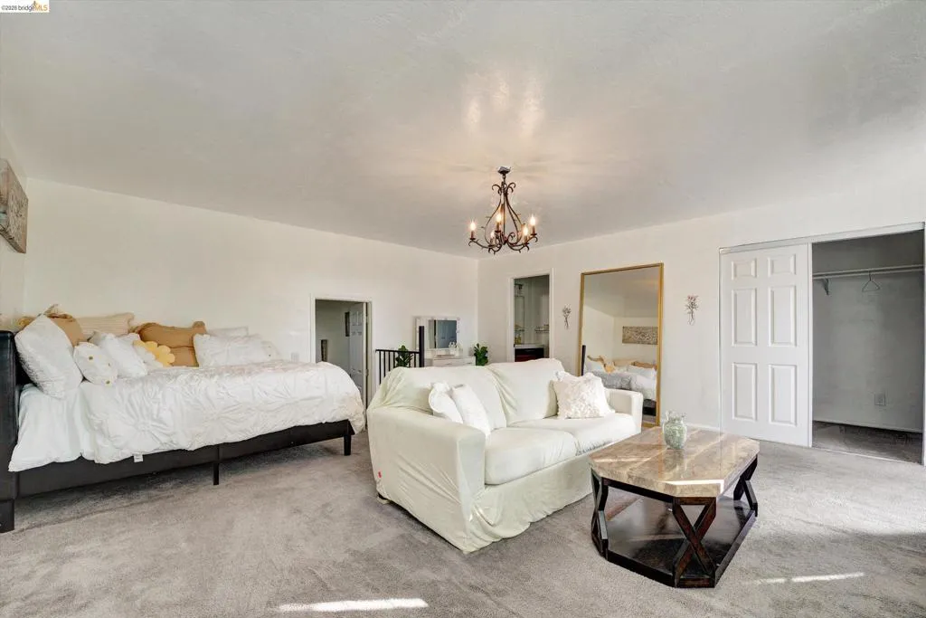 Spacious room featuring a decorative chandelier, dual sliding closet doors, and a marble-top coffee table