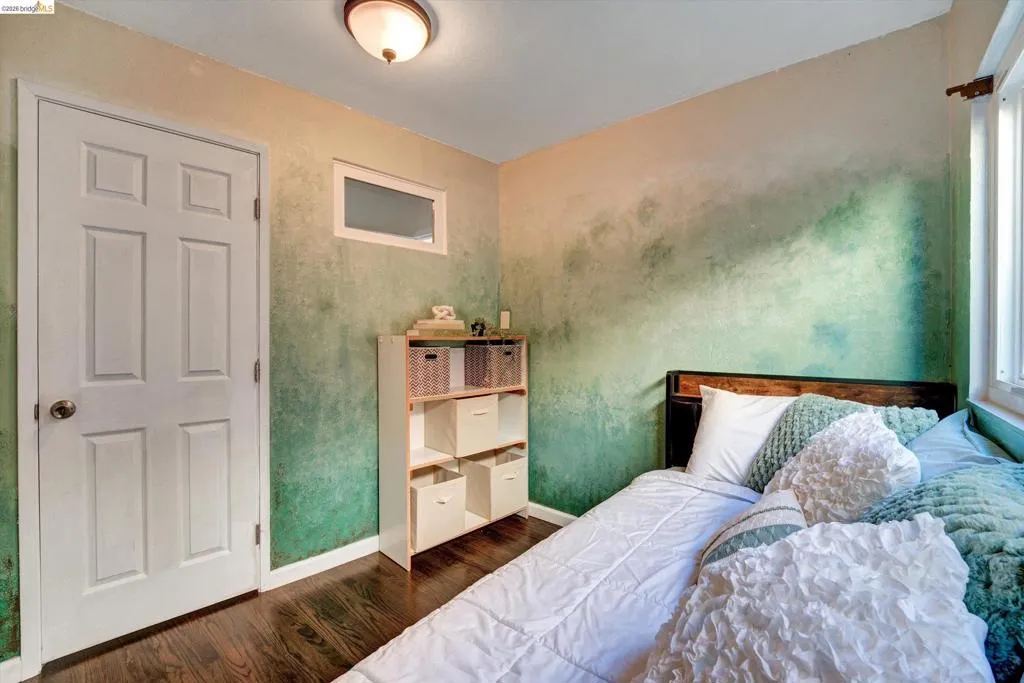 Hardwood flooring, painted accent wall, transom window, six-panel door, and a built-in shelving unit