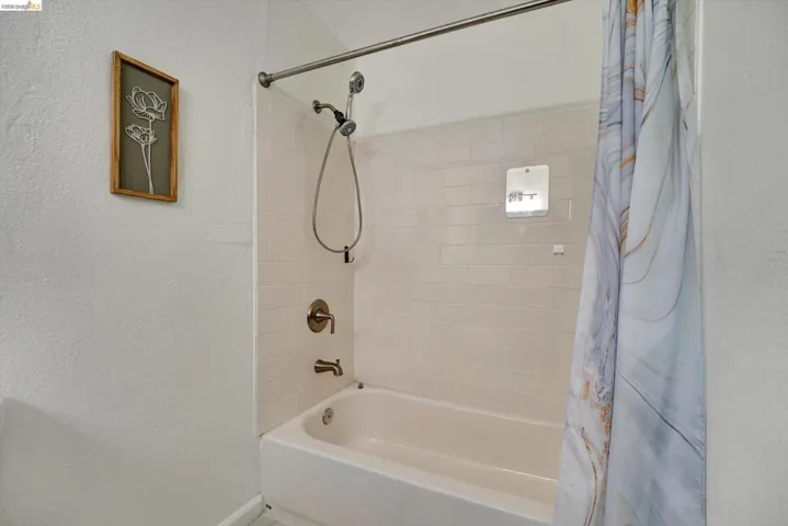 Bathtub with subway tile surround, brushed nickel fixtures, and a shower niche