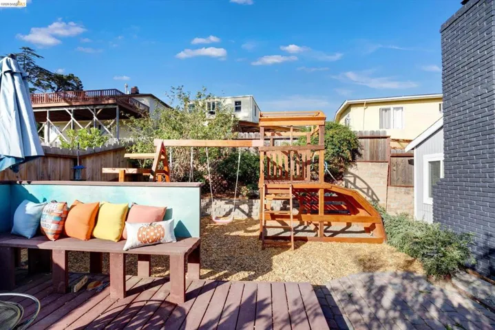 Wood-finish deck with built-in bench seating, wood chip ground cover, and a multi-level wooden play structure