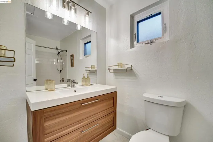 Wood-finish floating vanity with an integrated basin sink, brushed nickel faucet, large wall mirror, and modern vanity lighting