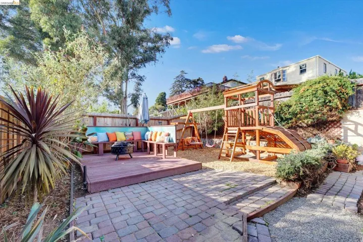 Expansive backyard featuring a paver patio, wood deck, and mature trees