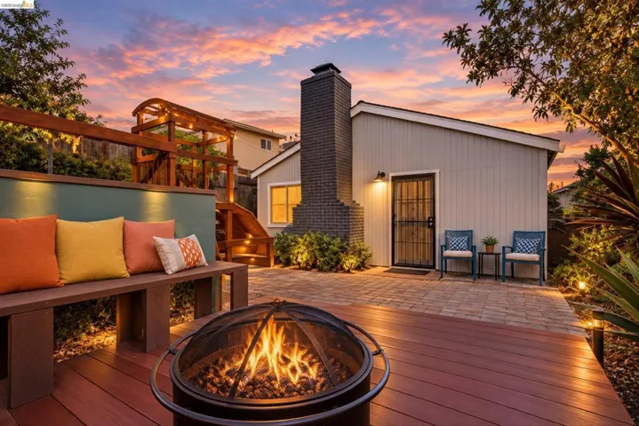 Multi-level exterior featuring a composite deck, paver patio, built-in bench seating, and an exposed brick chimney