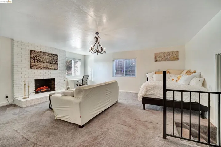 White brick fireplace with hearth, recessed windows, wrought iron chandelier, and black metal railing