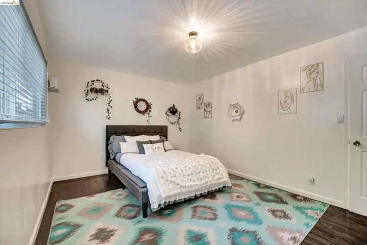 Recessed window with horizontal blinds, wood-finish flooring, white walls, and a ceiling-mounted light fixture
