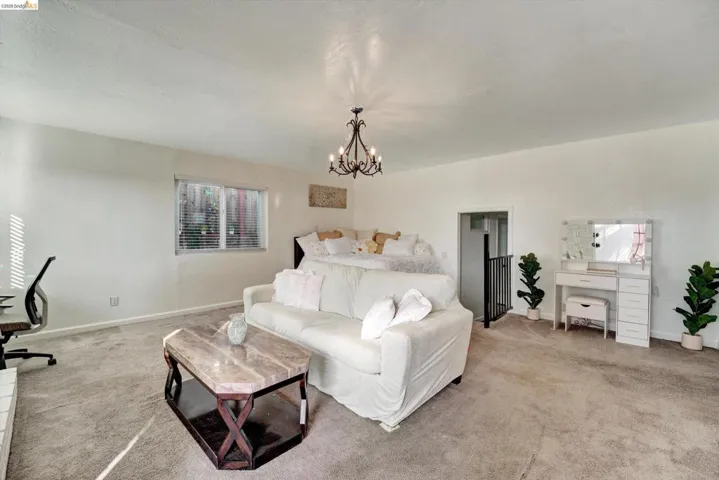 Recessed window with blinds, wrought iron chandelier, and neutral wall paint