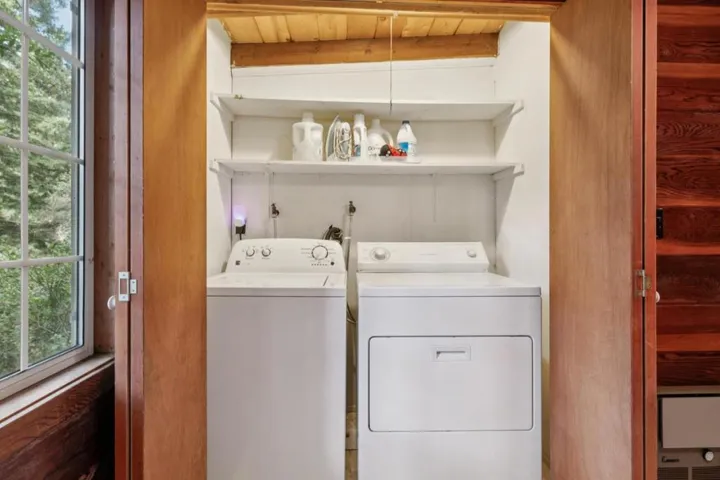 Full size washer and dryer with wall mounted storage shelves