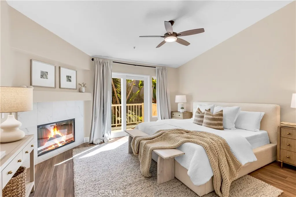 The primary bedroom has a gas fireplace, balcony, vaulted ceilings and a ceiling fan.