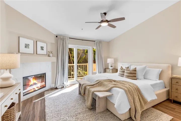 The primary bedroom has a gas fireplace, balcony, vaulted ceilings and a ceiling fan.