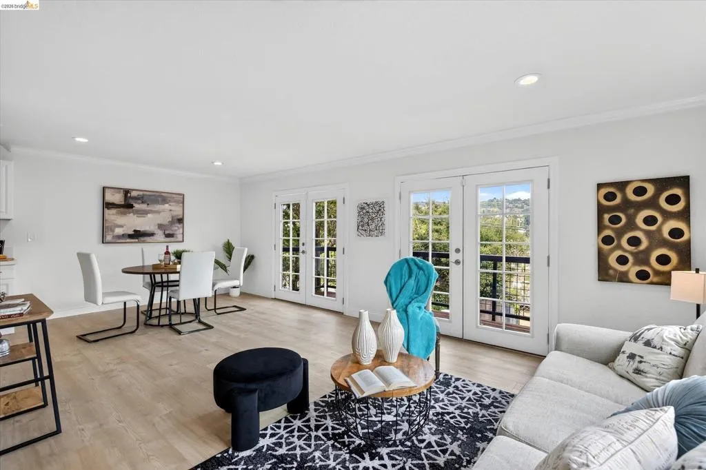French doors to a balcony, light wood-finish flooring, recessed lighting, and crown molding