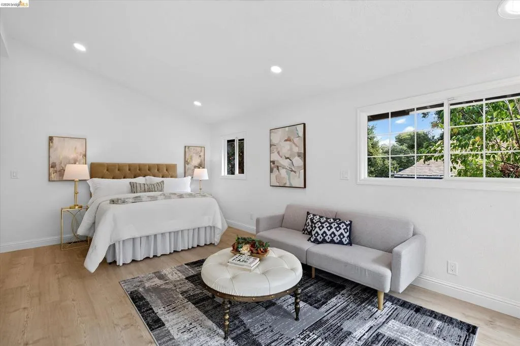 Vaulted ceiling with recessed lighting, wood-finish flooring, and white walls