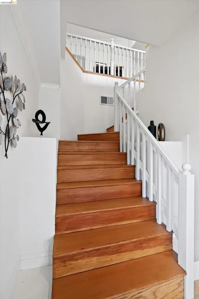 Staircase featuring wood-finish treads, white risers, and white balusters