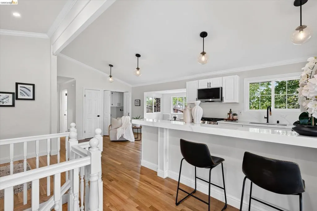 Kitchen featuring an island with white countertop, white shaker-style cabinetry, and stainless steel appliances