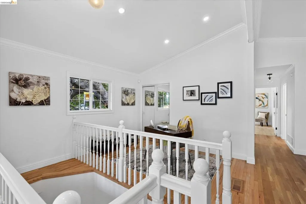 Hardwood flooring throughout, white painted railings, recessed lighting, and a double-paned window