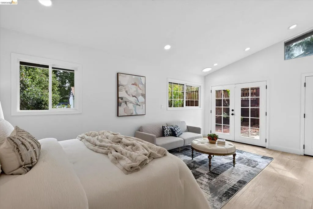 Vaulted ceiling, recessed lighting, wood-finish flooring, white French doors, and transom windows