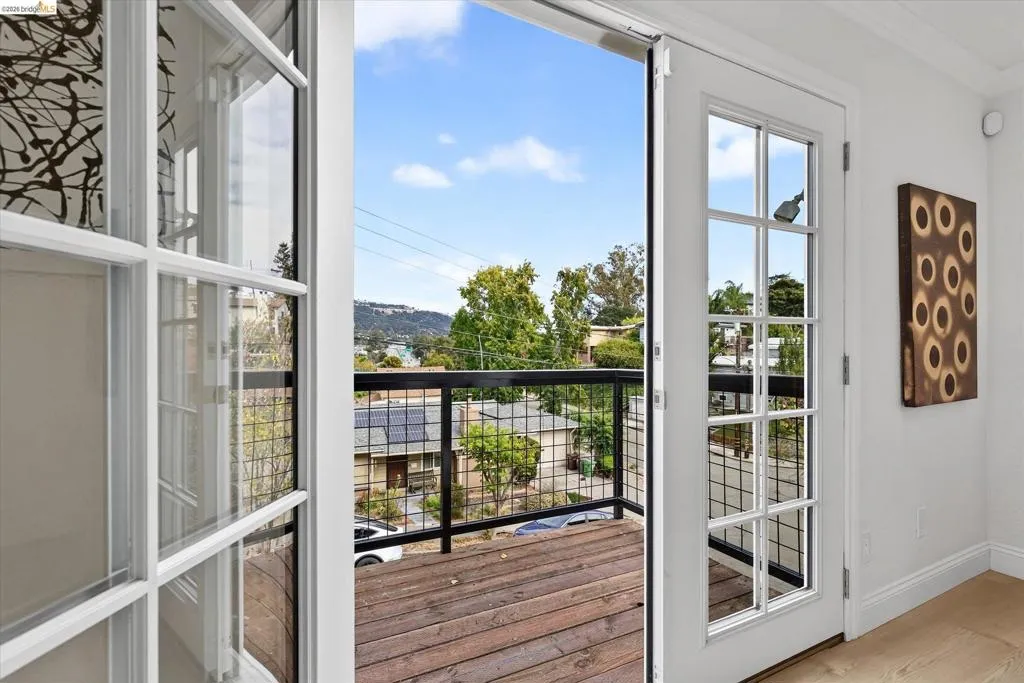 Sliding glass French doors opening to a wood-plank balcony with a metal railing