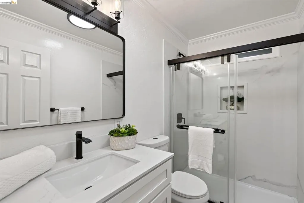 White vanity with an integrated rectangular sink, matte black faucet, and a framed mirror