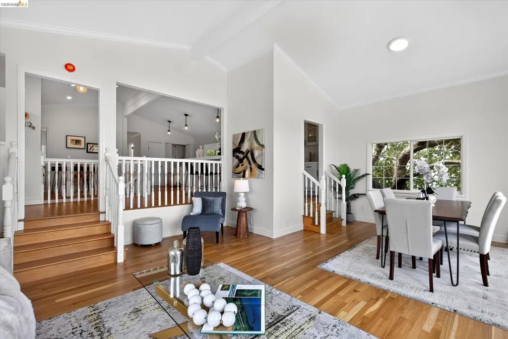 Recessed lighting, wood-finish flooring, white balustrade, window with natural light, vaulted ceiling