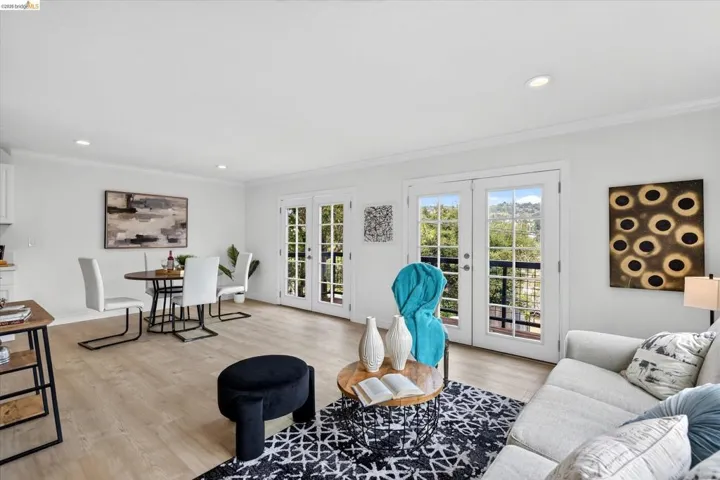 French doors to a balcony, light wood-finish flooring, recessed lighting, and crown molding