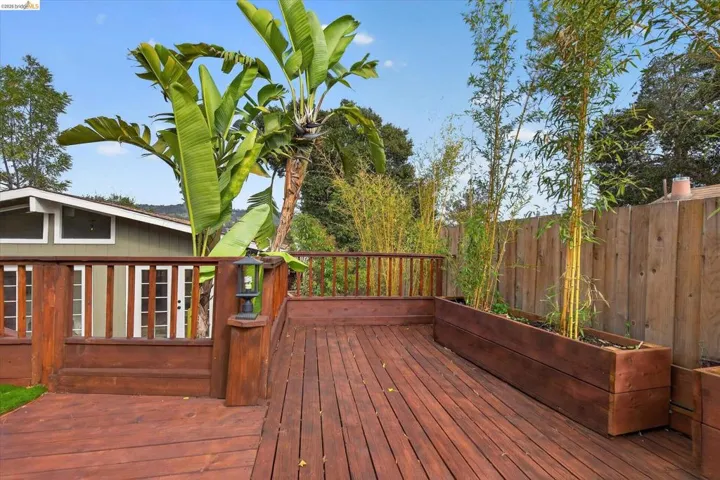 Spacious wood deck with integrated planter boxes, wood railing, and exterior lighting fixture