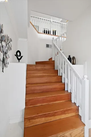 Staircase featuring wood-finish treads, white risers, and white balusters