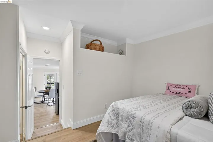 Light wood-finish flooring throughout, recessed ceiling lighting, crown molding, and white trim