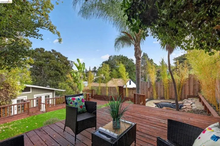 Expansive wood deck with a built-in planter, surrounded by mature trees and a private wooden fence