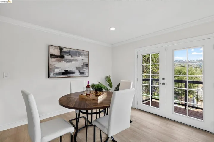 White walls with crown molding, wood-finish flooring, recessed lighting, and double French doors with a metal railing