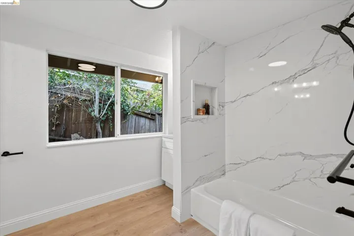 Bathtub with tile surround, integrated shower niche, and matte black shower fixtures